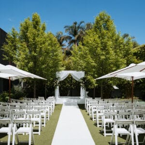 Acrylic stage (white) (3mW x 4mL x 40cmH) with White Wooden Chairs, Large White Garden Umbrellas and 10m Ivory Carpet