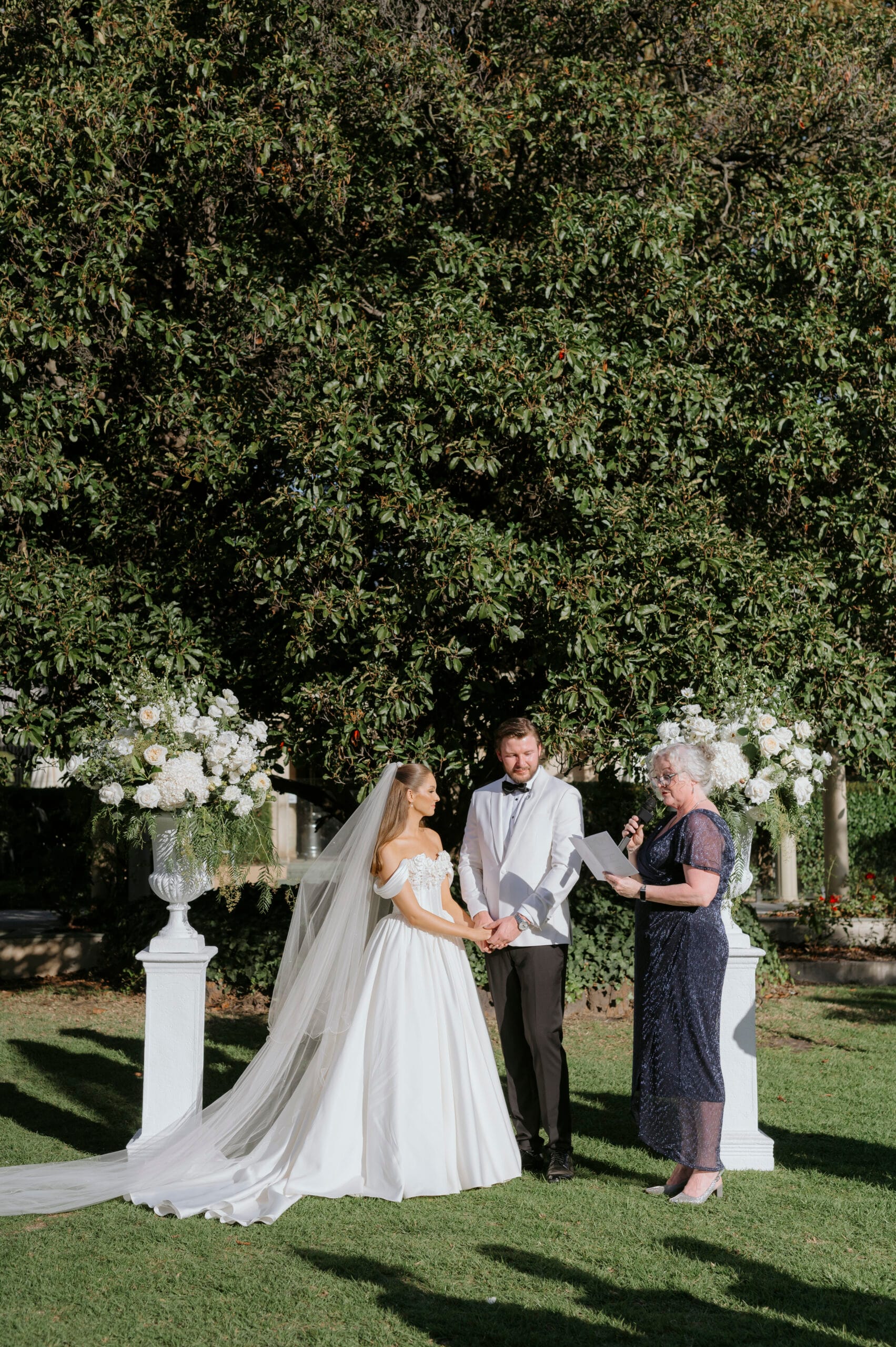 Textured slim white urn on textured slim white pedestal with fresh florals