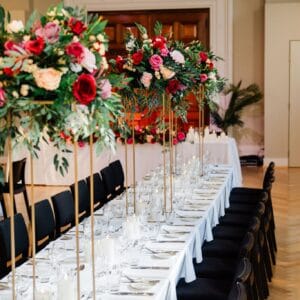 Gold stand with pink, red and beige silk floral arrangement with foliage