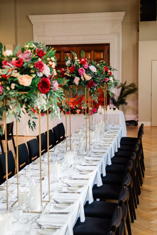 Gold stand with pink, red and beige silk floral arrangement with foliage